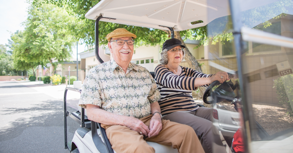 Senior couple exploring the community on a golf cart
