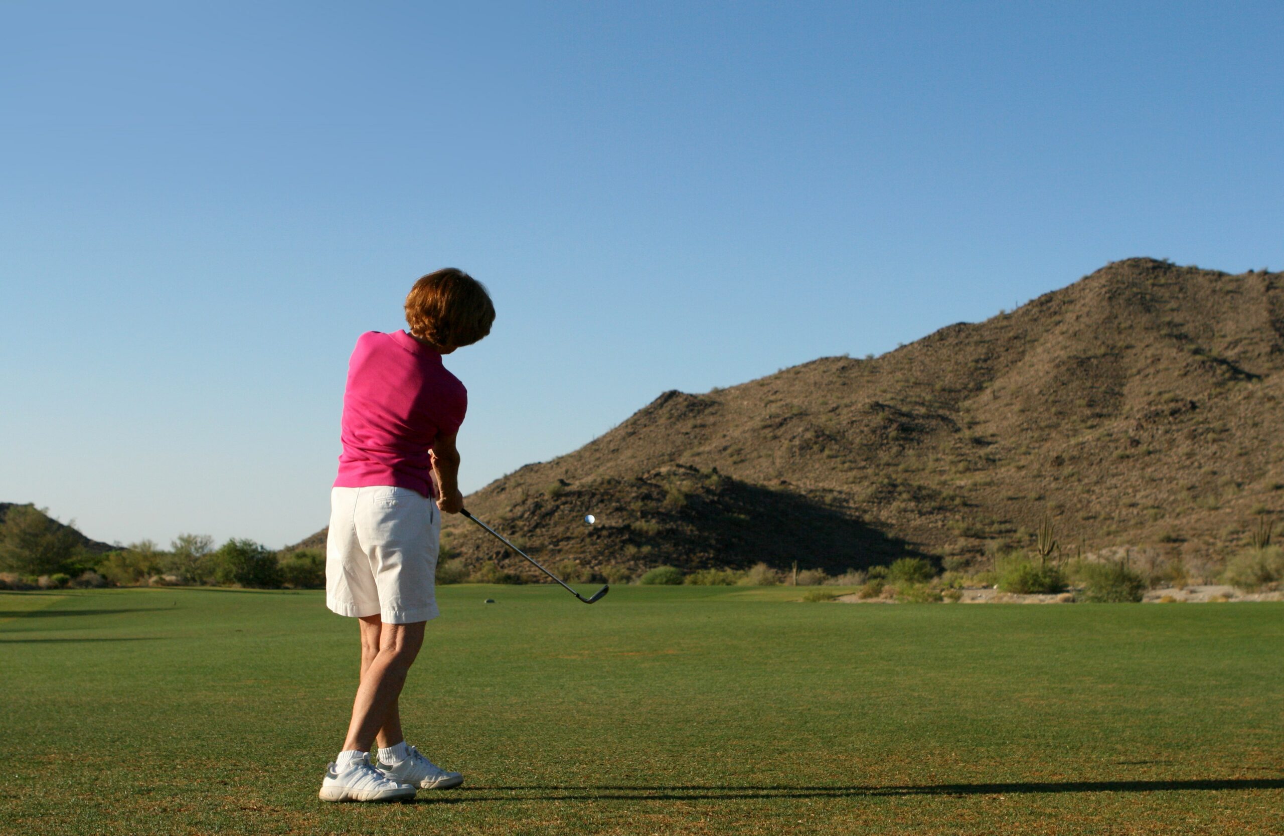 woman in pink shirt golfing in Phoenix, Arizona