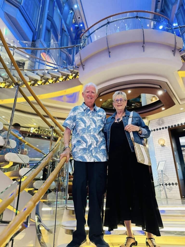 Sandy and Al smiling together on a staircase during a trip