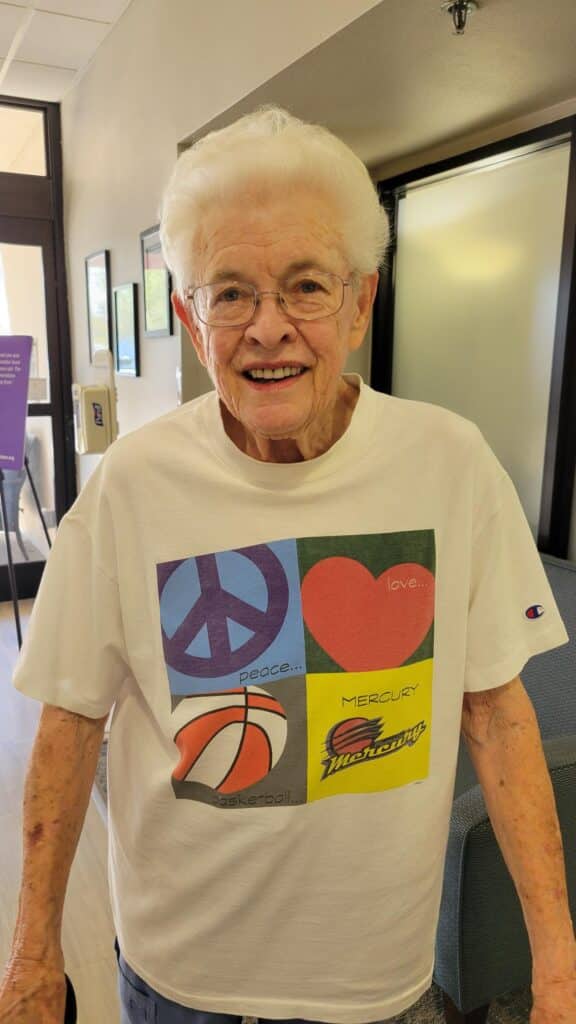 Older woman smiling while wearing a Phoenix Mercury basketball T-shirt.
